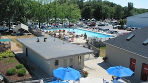 A rooftop pool area with lounge chairs and umbrellas, surrounded by parked cars and buildings. - The Staterooms 2J, Directions, Newly Built, Seasonally Heated Pool, Beach Nearby (Holland)