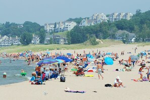 Uma praia cheia de gente, guarda-sóis e cadeiras de praia.