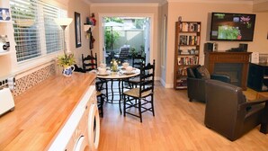 Un salon chaleureux comprenant un coin repas, une cheminée et une bibliothèque.
