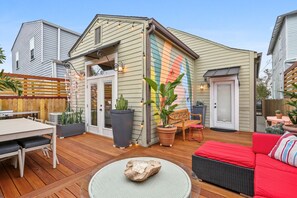 A patio with a wooden table and chairs, a red sofa, and potted plants.