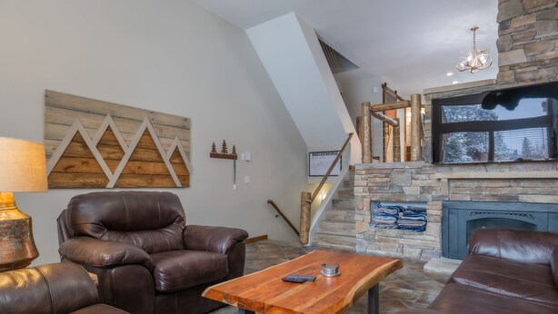 Un salon moderne avec des canapés en cuir, une table basse en bois et une cheminée en pierre.