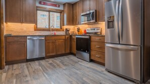 Une cuisine moderne avec des meubles en bois, des appareils électroménagers en acier inoxydable et un pare-feu en pierre.