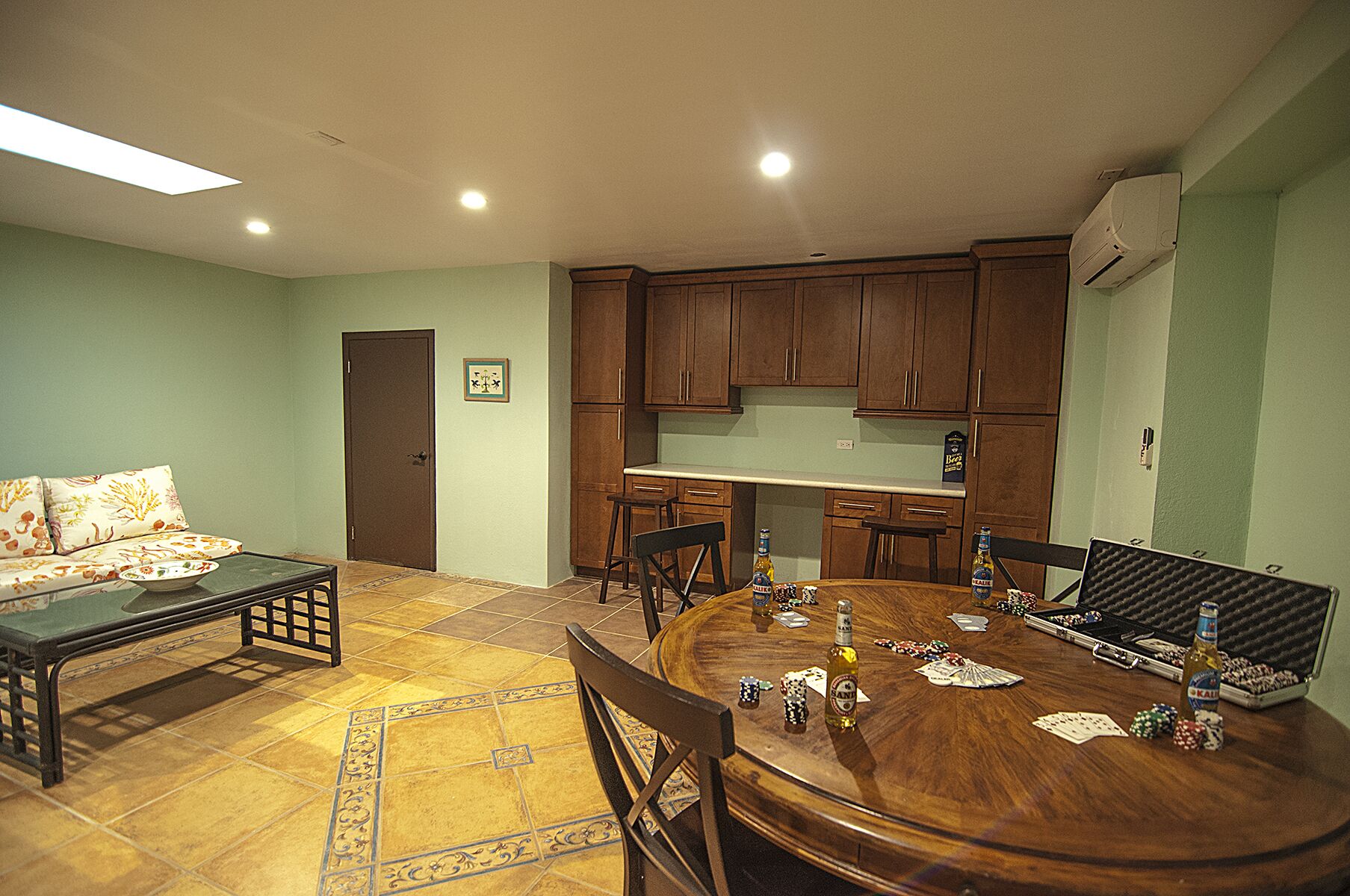 A dining area with a round wooden table, chairs, and a sofa with a patterned cushion.