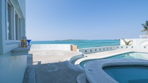 A pool area with a view of the ocean, a lounge chair, and a bar area with bottles. - Location!!! no car needed, Luxury Oceanfront, Our home on HGTV (Nassau)