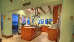 A spacious kitchen with a large island, wooden cabinets, and a view of the beach through the windows. - Location!!! no car needed, Luxury Oceanfront, Our home on HGTV (Nassau)