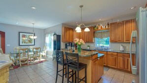 Una cocina amplia con armarios de madera, encimera de granito y una isla central con taburetes de bar.
