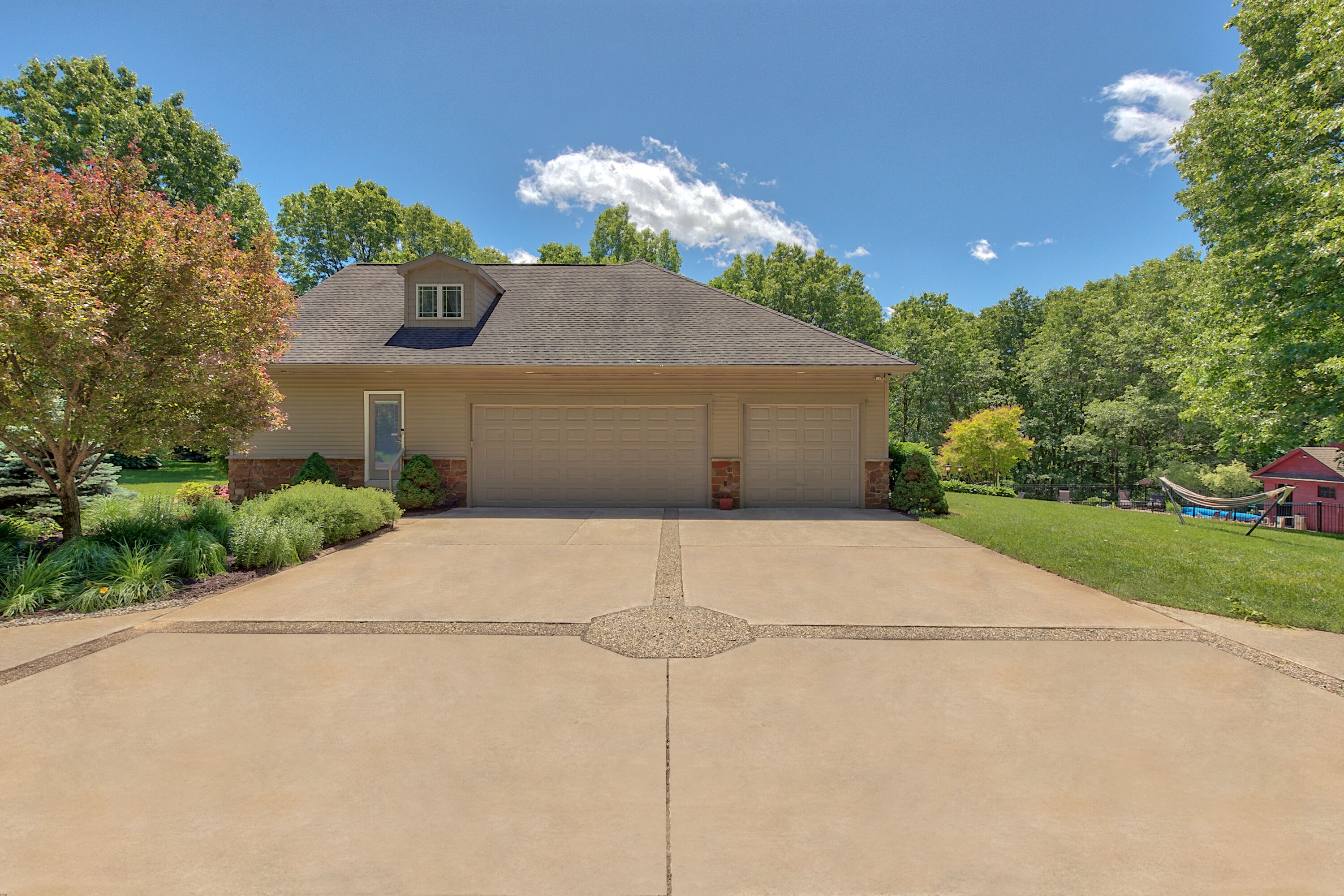 A two-story house with a garage, surrounded by a well-maintained lawn and trees.