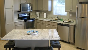 A kitchen with a central island, stainless steel appliances, and beige cabinetry. - DESTIN HARBORWALK, 3 bedrooms w/ Boatdock (destin)