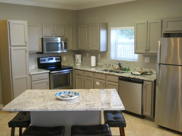 A kitchen with a central island, stainless steel appliances, and beige cabinetry.