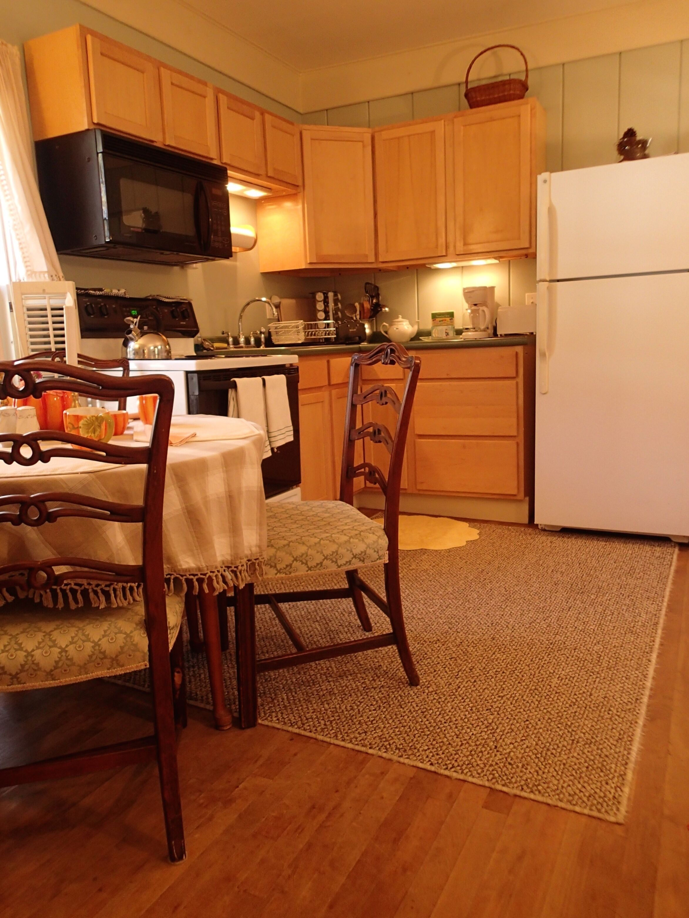 A kitchen with wooden cabinets, a microwave, a refrigerator, and a dining table with chairs.