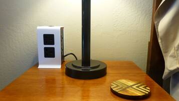 Una mesa de madera con una lámpara negra, un cuadro de luces blanco y un posavasos de madera.