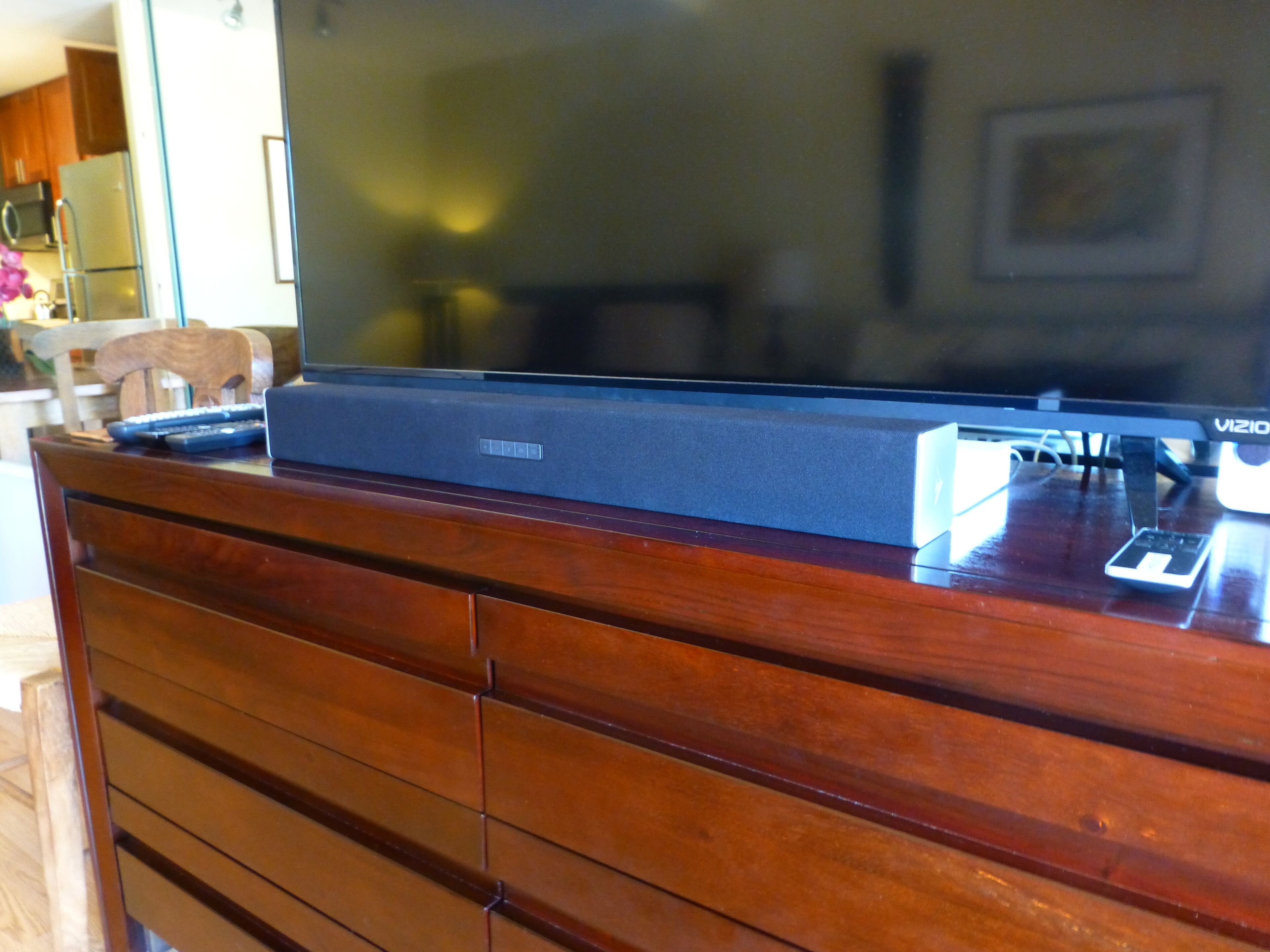 A flat-screen TV on a wooden cabinet with a remote control.