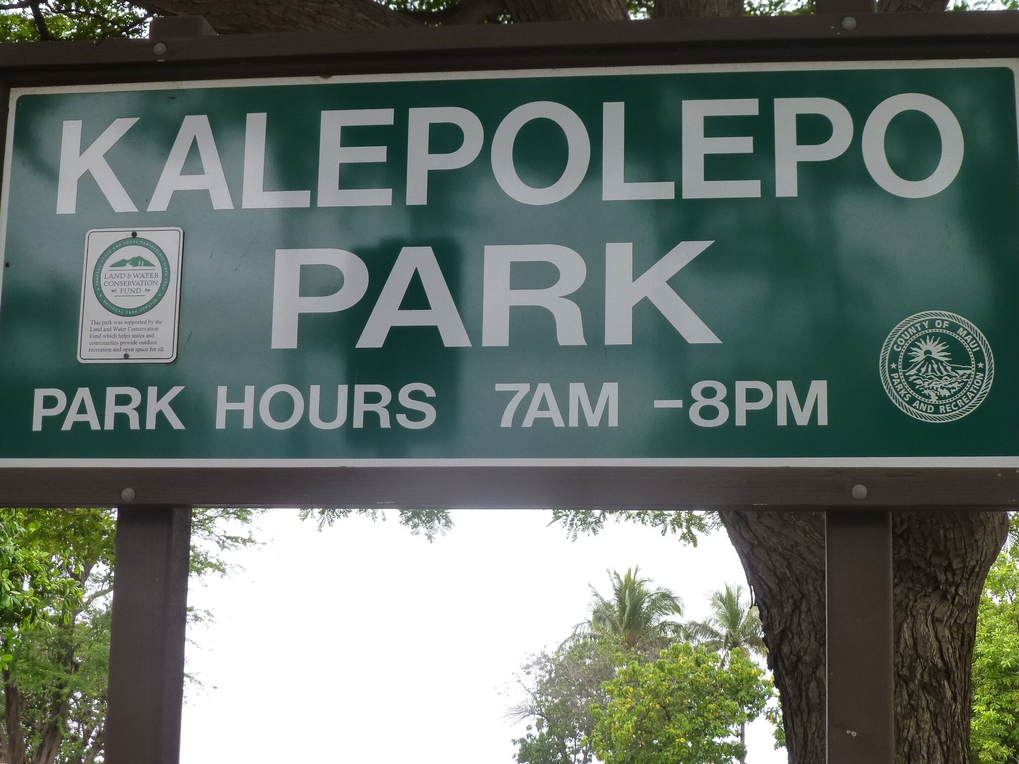 A sign for Kalepolo Park indicating park hours from 7 AM to 8 PM.