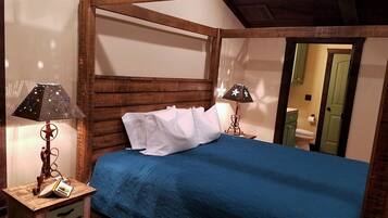 A bedroom with a wooden headboard, a blue bedspread, white pillows, and two lamps with star patterns.
