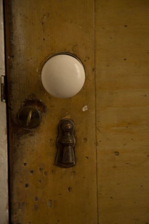 Une porte en bois avec un bouton de poignée rond et blanc et une poignée de porte en métal.
