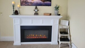 A fireplace with a mantel, a clock, and a painting above it.