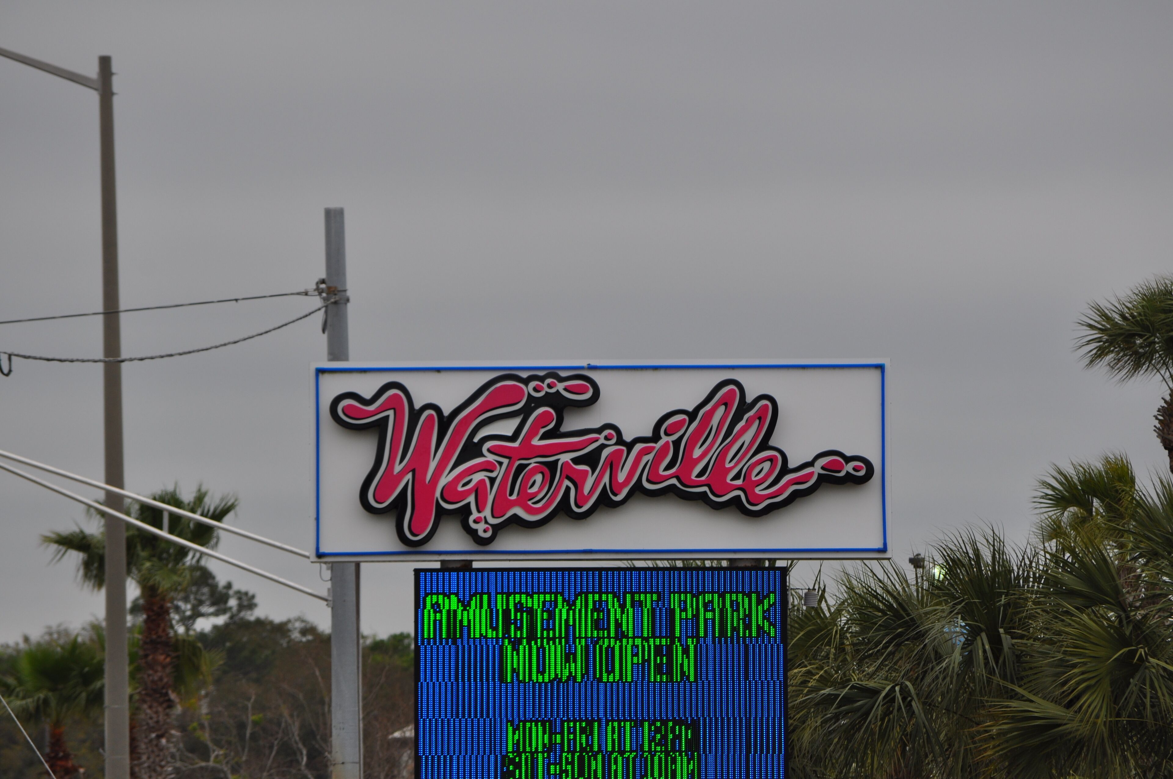 A sign with the name 'Waterville' and a digital display stating 'AMUSEMENT PARK NOW OPEN'.
