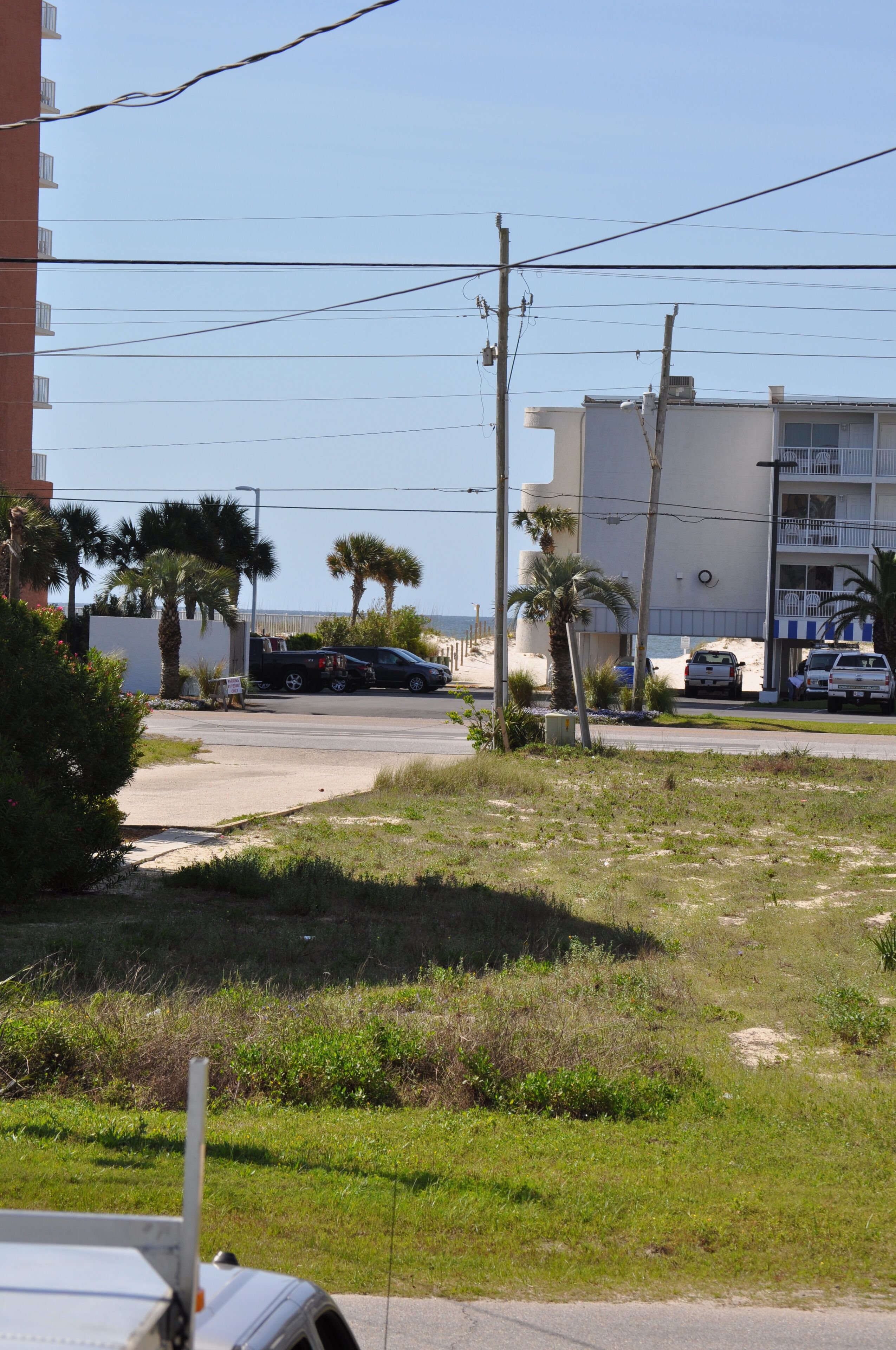 A street view with a building, parked vehicles, and a clear sky.