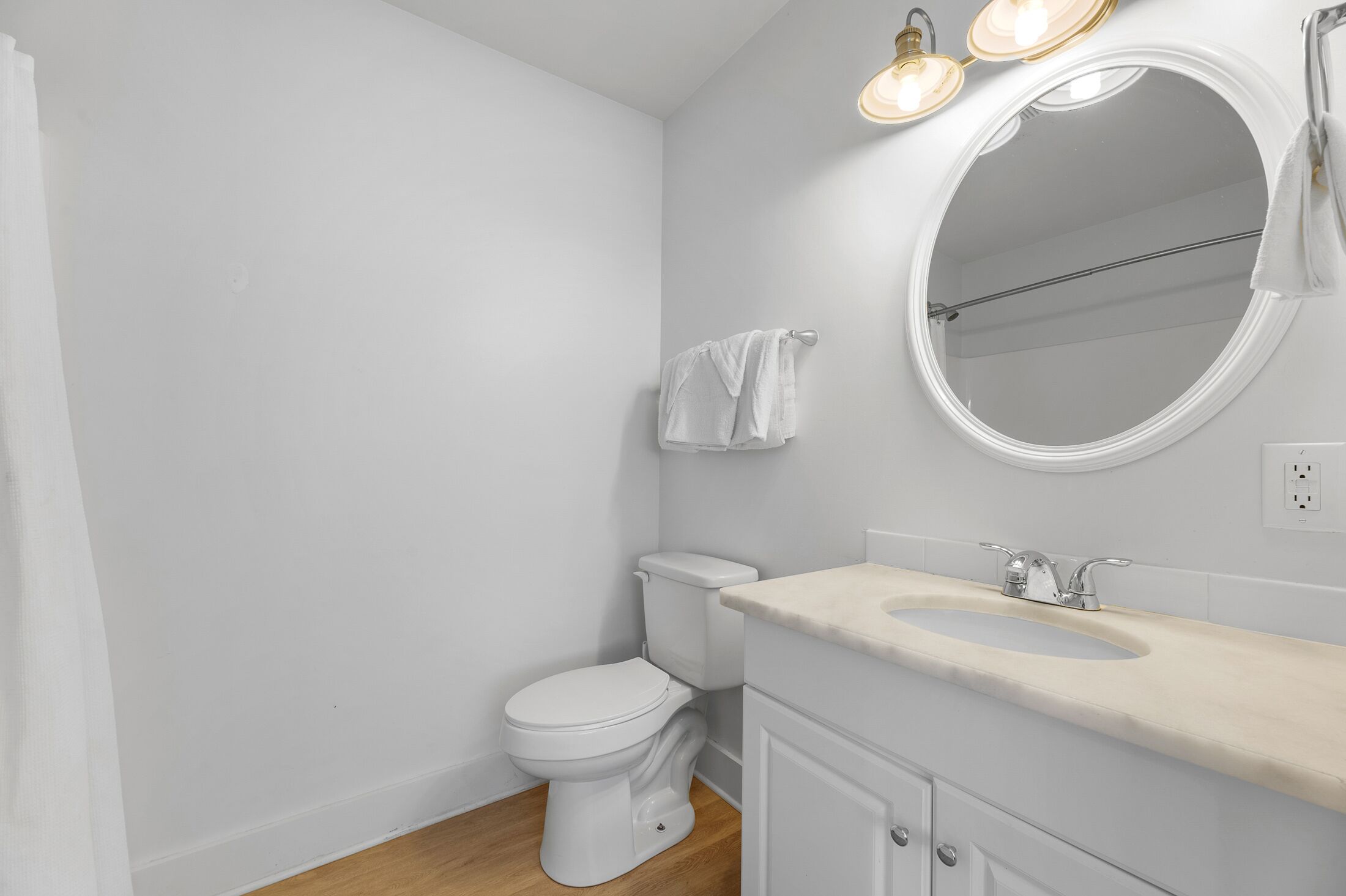 A bathroom with a toilet, sink, mirror, and towel rack.