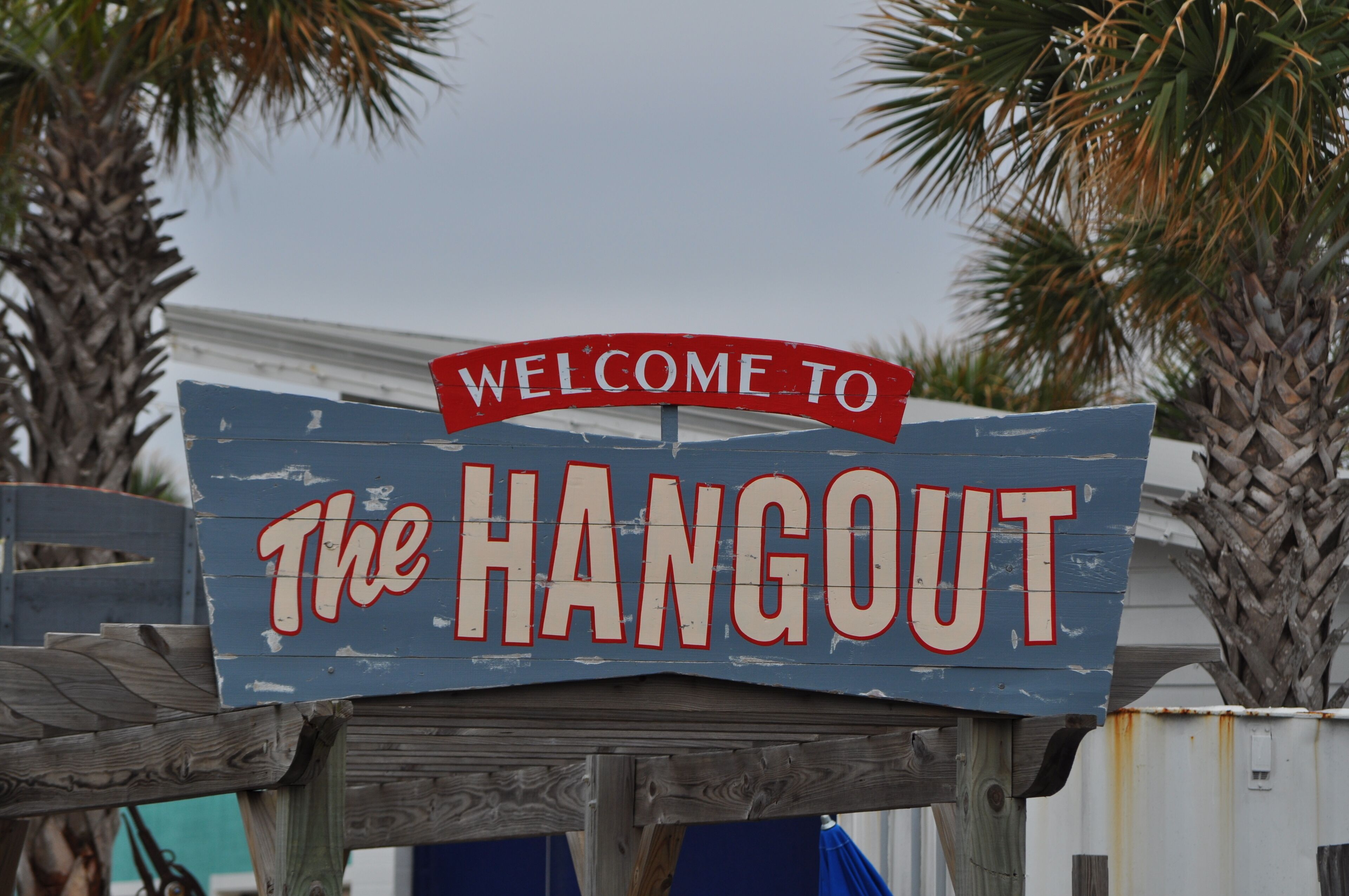 A wooden sign with "WELCOME TO The HANGOUT" written on it.