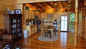 Interior de una cabaña de madera con comedor, cocina y sala de estar.