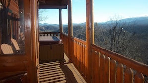 Una cabaña de madera con balcón y vistas a un paisaje montañoso.