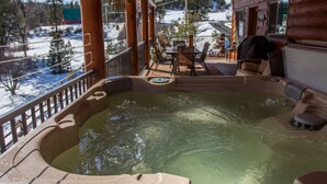 A hot tub with a view of a snowy landscape, wooden deck, and outdoor seating area. - Stunning Log Cabin w/ Hot Tub, 3 Kings+ 4 BRms & loft - 2 flat screen TV's (Garden Valley)