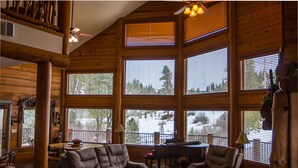 A spacious living room with large windows, a fireplace, and a dining area. - Stunning Log Cabin w/ Hot Tub, 3 Kings+ 4 BRms & loft - 2 flat screen TV's (Garden Valley)