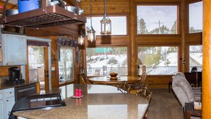 A kitchen with granite countertops, wooden cabinets, and a dining area with a table and chairs. - Stunning Log Cabin w/ Hot Tub, 3 Kings+ 4 BRms & loft - 2 flat screen TV's (Garden Valley)