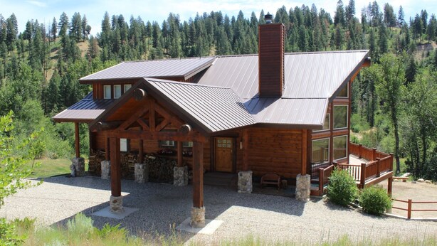A log cabin with a large deck, stone pillars, and a gravel driveway. - Stunning Log Cabin w/ Hot Tub, 3 Kings+ 4 BRms & loft - 2 flat screen TV's (Garden Valley)