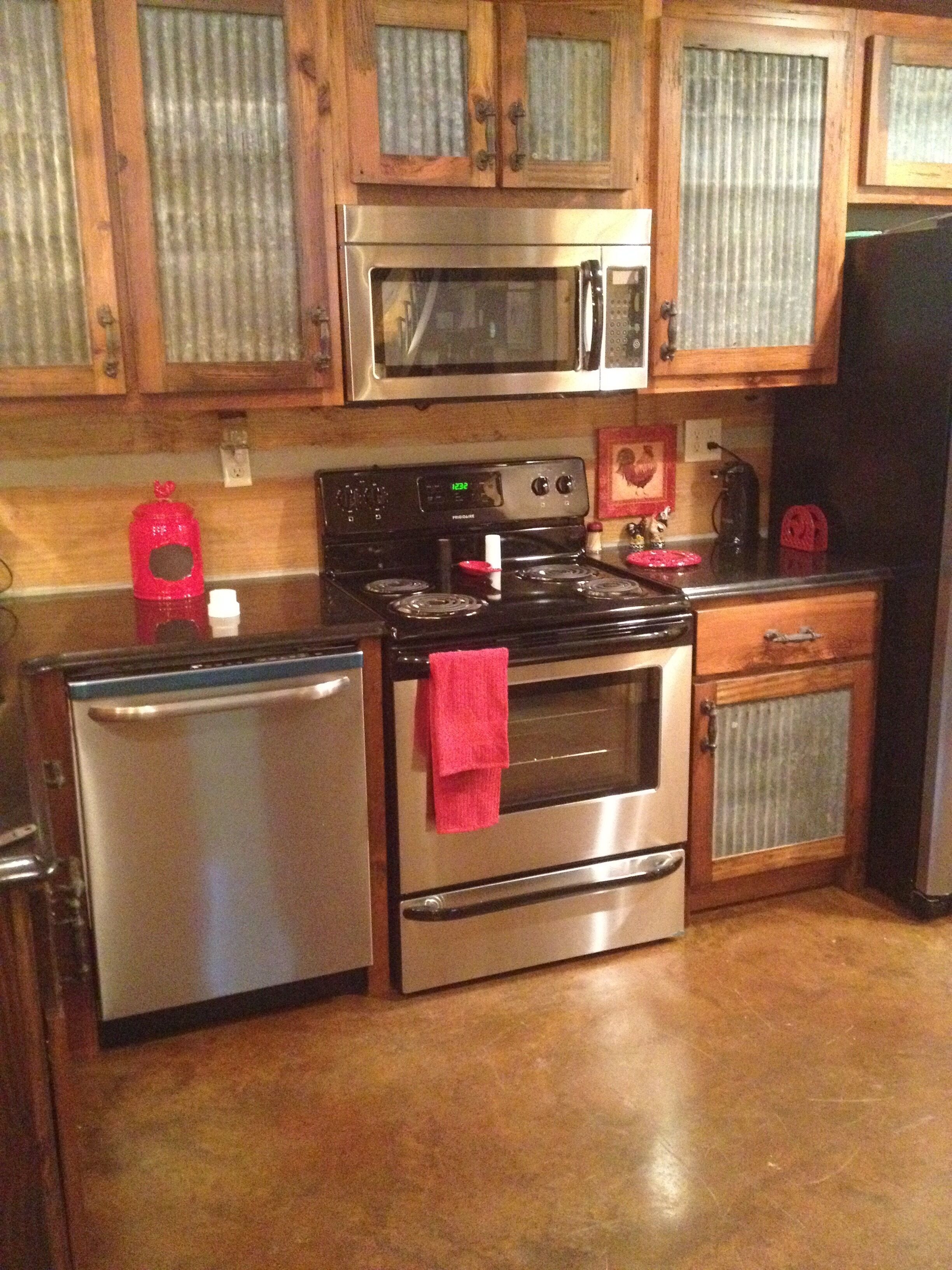 A kitchen with wooden cabinets, stainless steel appliances, and a red towel hanging on the oven handle.