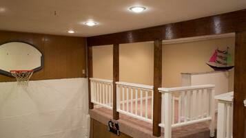Enjoy a game of hoops in this spacious room with a basketball hoop and a cozy staircase leading to the upper level.