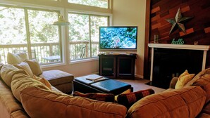 Un salon doté d’une grande fenêtre, d’un téléviseur, d’une cheminée et d’une décoration en forme d’étoile.