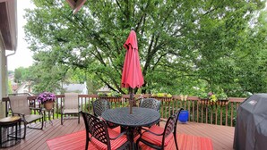 A wooden deck with a round table and chairs, surrounded by a red rug. - 
Luxe  Fully Furnished 5 Star Home in Hyde Park/ Cincinnati (Cincinnati)
