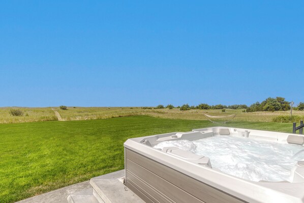 A hot tub in a grassy field with a clear blue sky.