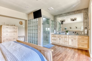 Enjoy a spacious bathroom with a large mirror, glass shower enclosure, and a vanity with multiple drawers.