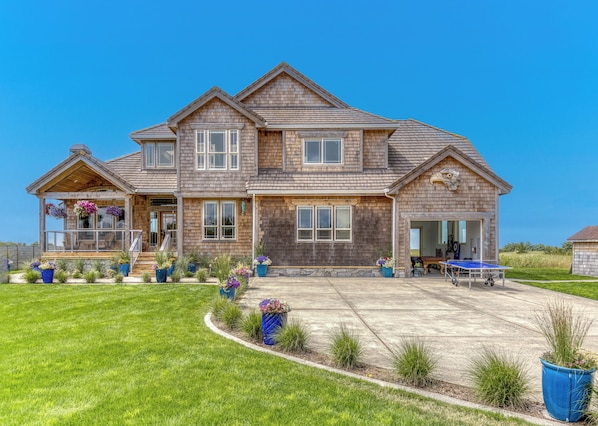 A two-story house with a covered porch, a garage, and a tennis court.