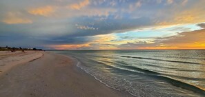 A beach with a curved shoreline and calm waves.