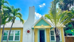 Una casa amarilla con puerta azul y el número 2202.