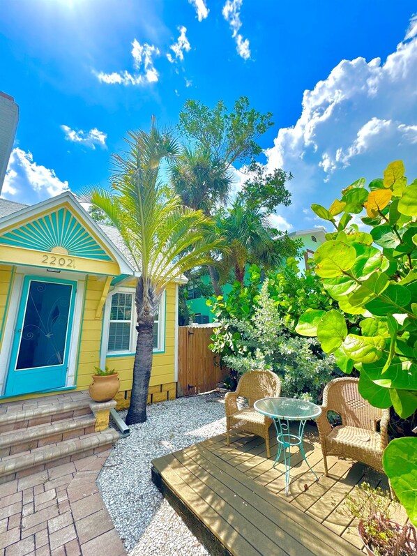 A yellow house with a blue door and a number '2202' on the front. - Steps 2 Beach- Cottage w/king bd +2bikes +parking (St Pete BEach)