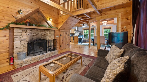 A spacious living area with a stone fireplace, wooden ceiling beams, a comfortable couch, and a television. - Mentone “Rest Easy” - Tranquil Serenity & Pet Friendly (Mentone)