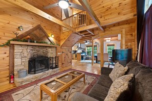 A spacious living area with a stone fireplace, wooden ceiling beams, a comfortable couch, and a television. - Mentone “Rest Easy” - Tranquil Serenity & Pet Friendly (Mentone)