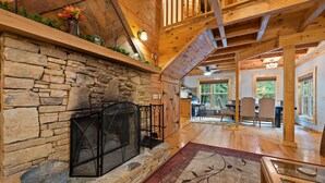 A stone fireplace with a black screen, wooden beams, and a dining area with chairs and a table. - Mentone “Rest Easy” - Tranquil Serenity & Pet Friendly (Mentone)