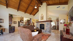 A spacious living room with a stone fireplace, a large brown leather sofa, and a dining area with a wooden table and chairs.