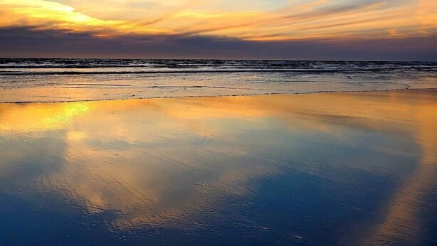 Uma praia com mar calmo e céu claro.