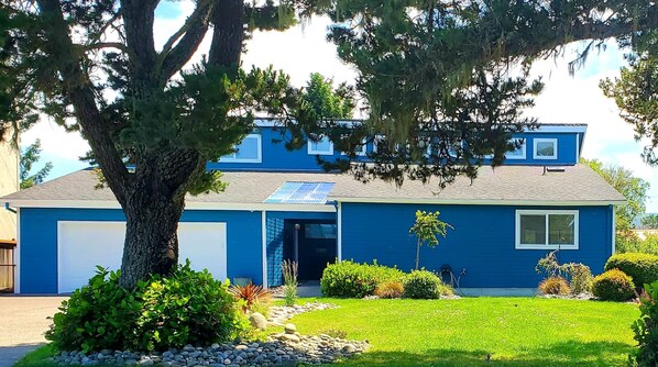 A two-story house with a garage, solar panels, and a well-maintained lawn. - Riverside Beach House (Seaside)