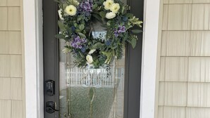 Una puerta principal gris oscuro adornada con un arreglo decorativo y una pequeña planta en maceta a un lado.