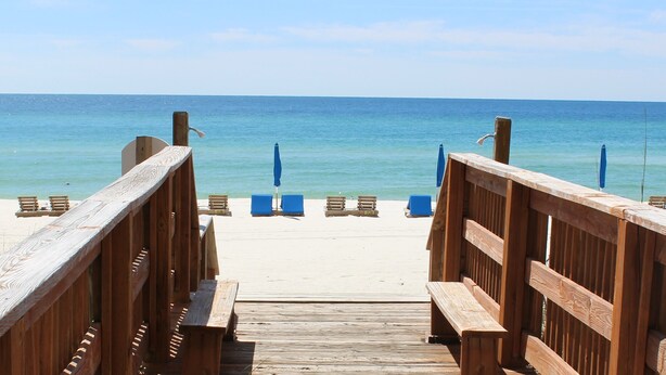A wooden boardwalk leading to beach chairs and umbrellas. - 3rd floor, Right on the Beach! Cozy, Comfy, & a Stunning View! Near Pier Park! (Panama City Beach)