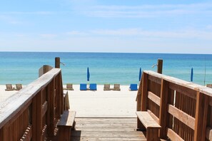 A wooden boardwalk leading to beach chairs and umbrellas. - 3rd floor, Right on the Beach! Cozy, Comfy, & a Stunning View! Near Pier Park! (Panama City Beach)
