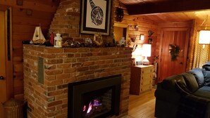Un saló acollidor amb una llar de pedra, parets de fusta i un sofà confortable.